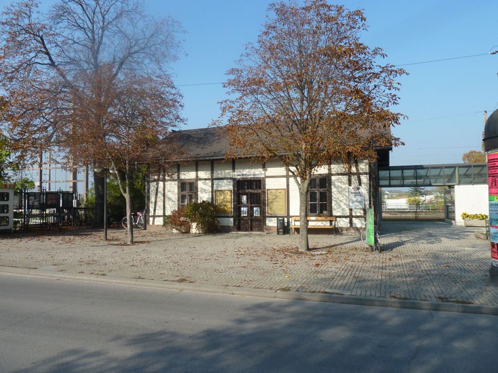 A Deutsch-Wagram vasúti múzeum régi épülete, előtérben fákkal.