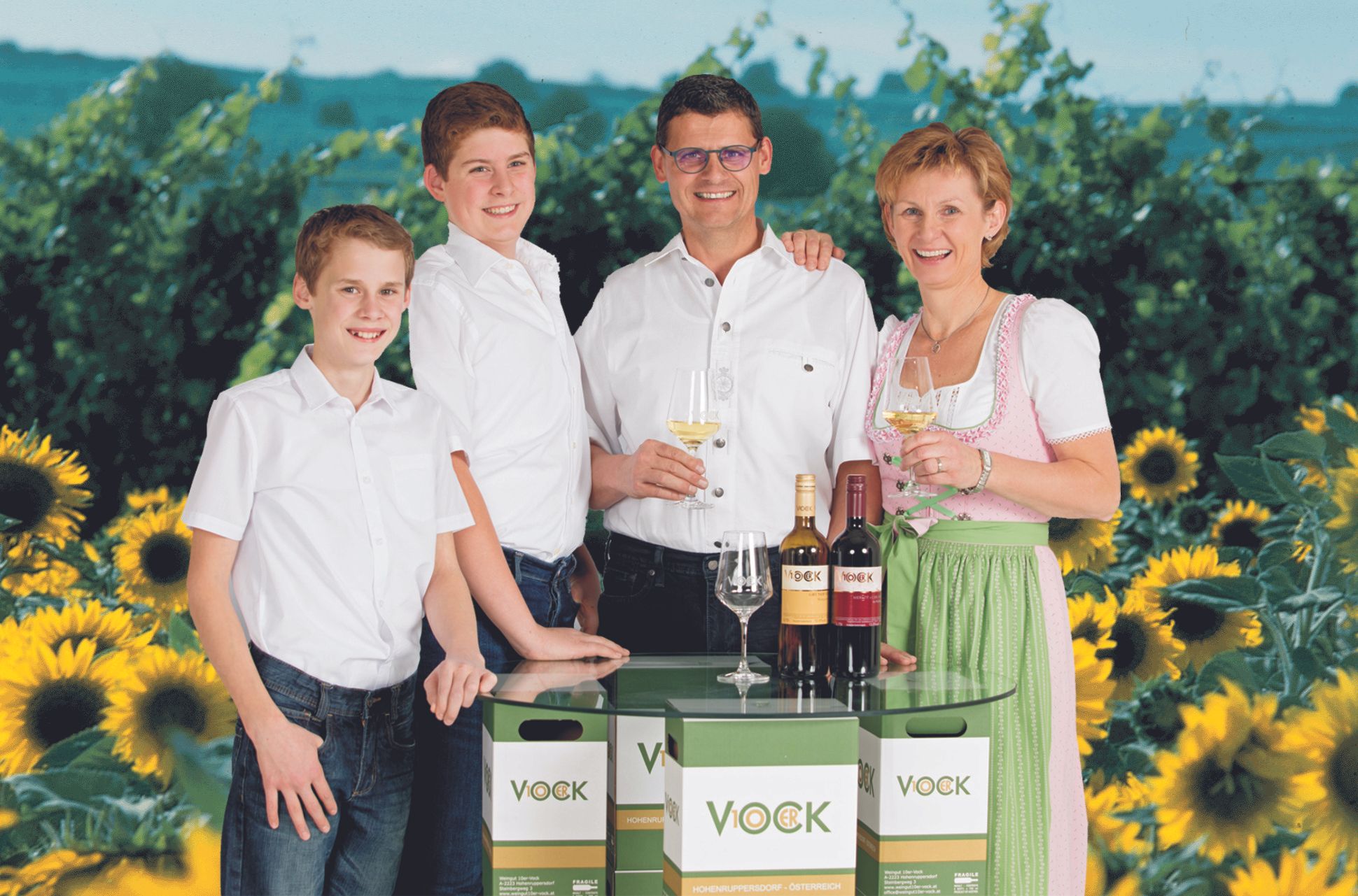Család borosüvegekkel és napraforgókkal a háttérben.