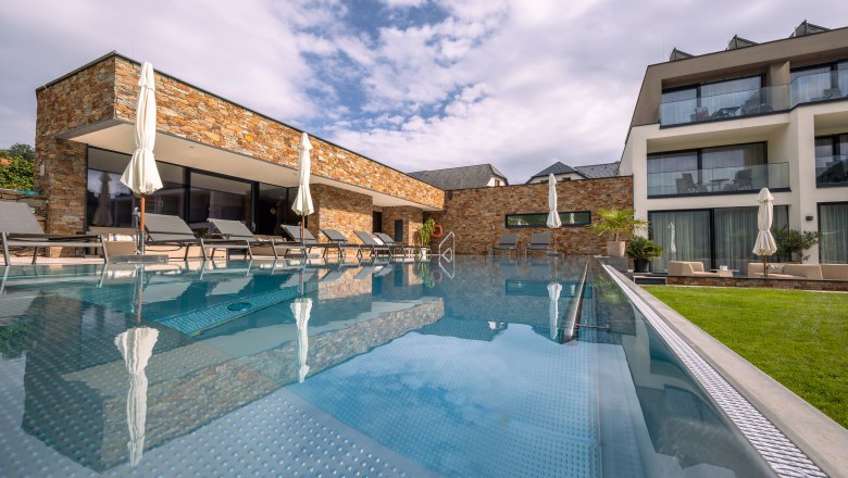 Boutique hotel WeinSpitz, © Niederösterreich Werbung / Maximilian Pawlikowsky Egy modern szálloda külső nézete medencével és nyugágyakkal.