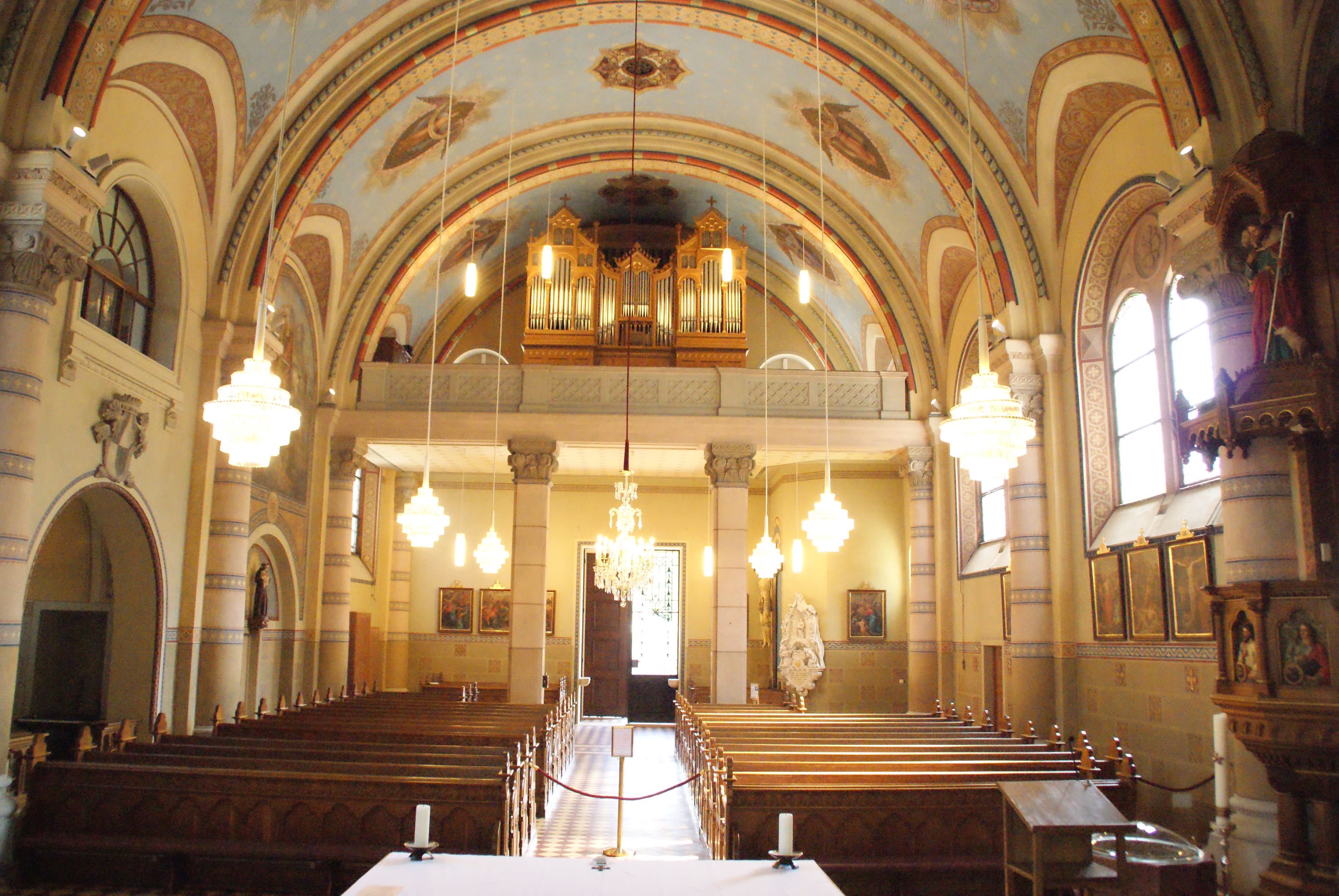 A Szent Márton plébániatemplom belső nézete a padokkal, orgonával és csillárokkal.