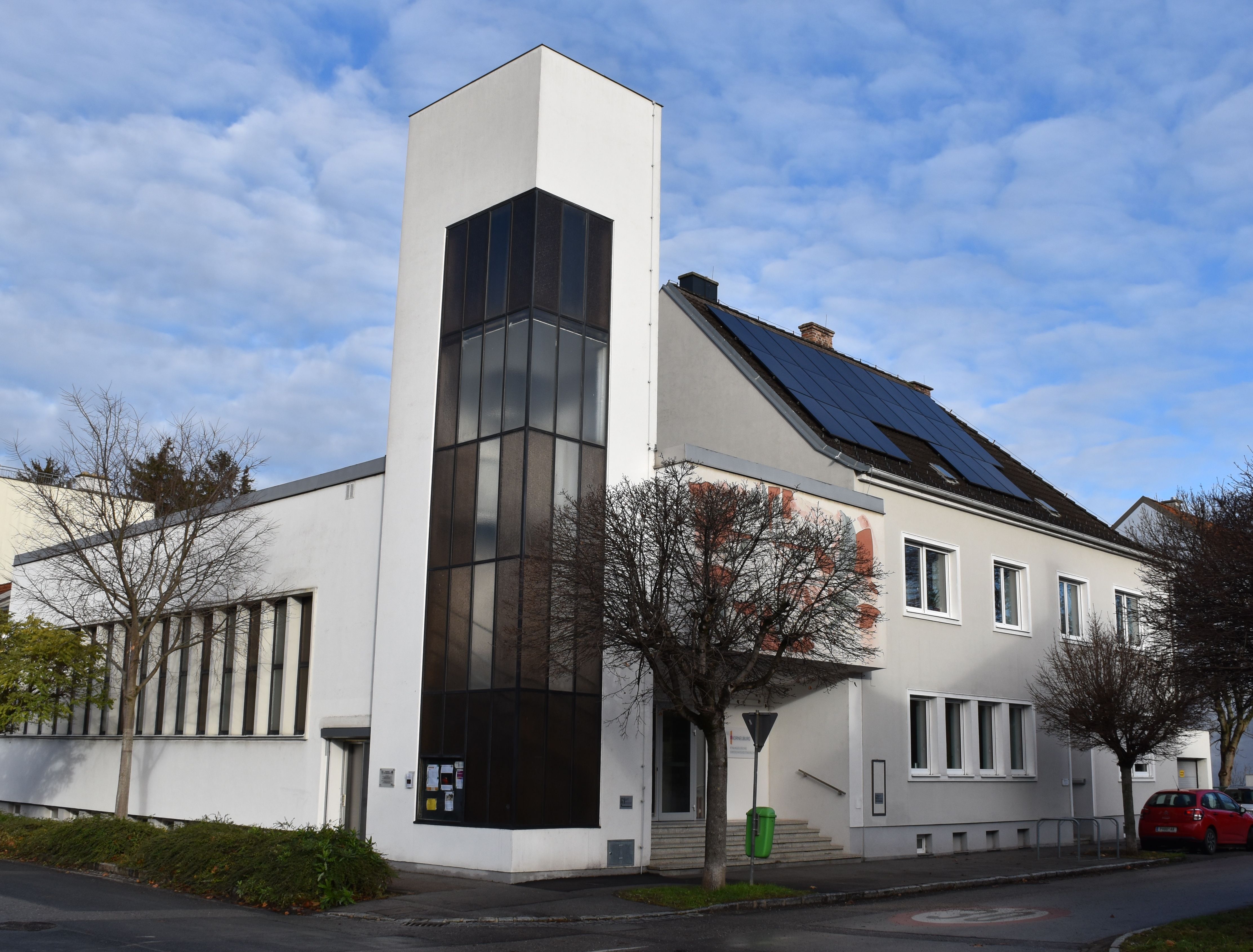 Modern templom fehér homlokzattal és napelemekkel a tetőn.