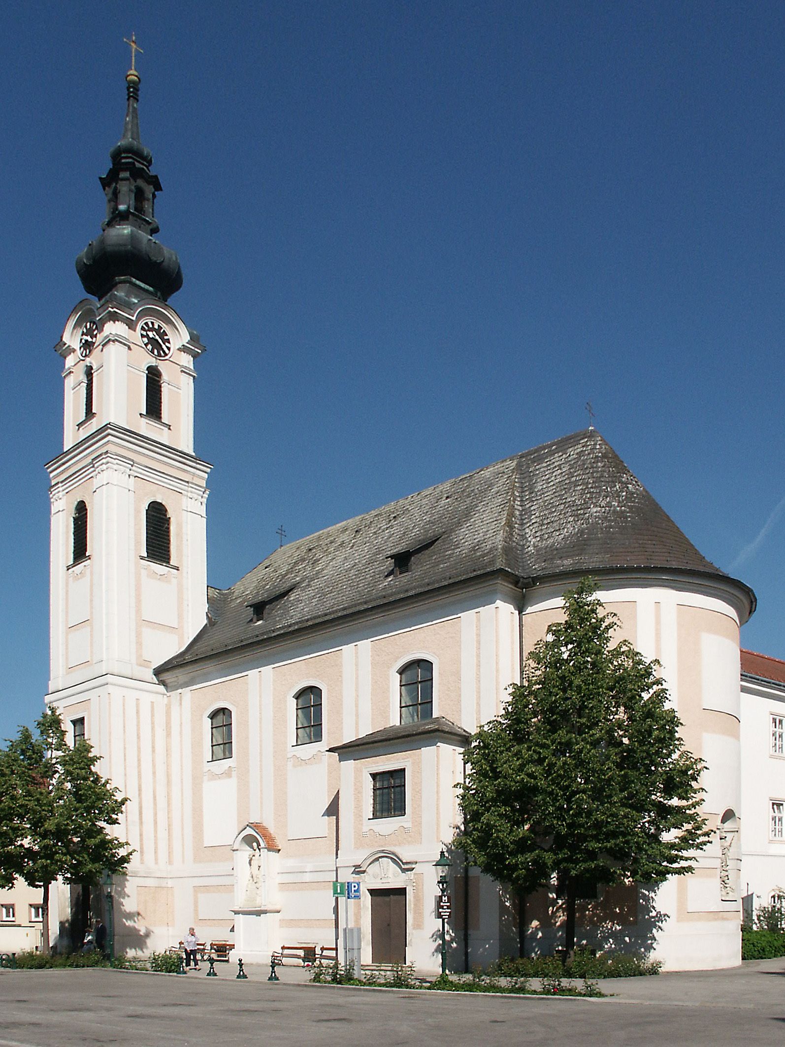A tullni Minoritenkirche-templom a kék égbolt előtt, lenyűgöző tornyával és barokk építészetével.