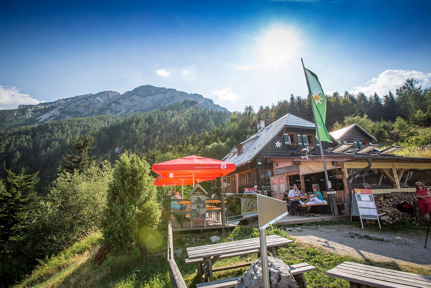 Edelweiss kunyhó a Schneeberg-hegyen napernyőkkel és hegyi háttérrel.