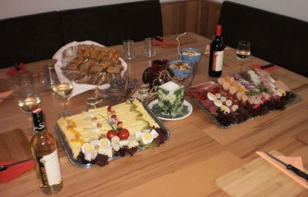 Terített asztal sajt- és kolbásztálakkal, kenyérrel, borral és poharakkal.