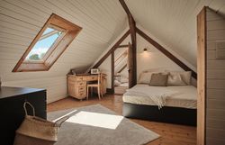 Rusztikus kőház faajtóval, paddal és virágokkal az előtérben.