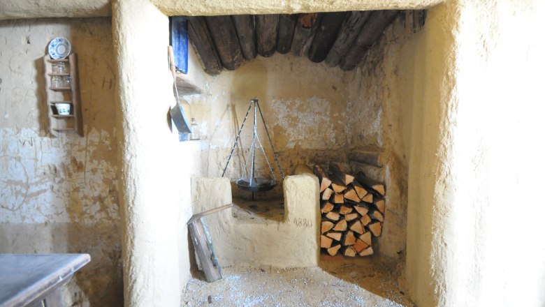 Belső n&eacute;zet egy rusztikus szob&aacute;b&oacute;l, kandall&oacute;val &eacute;s fakupacokkal.