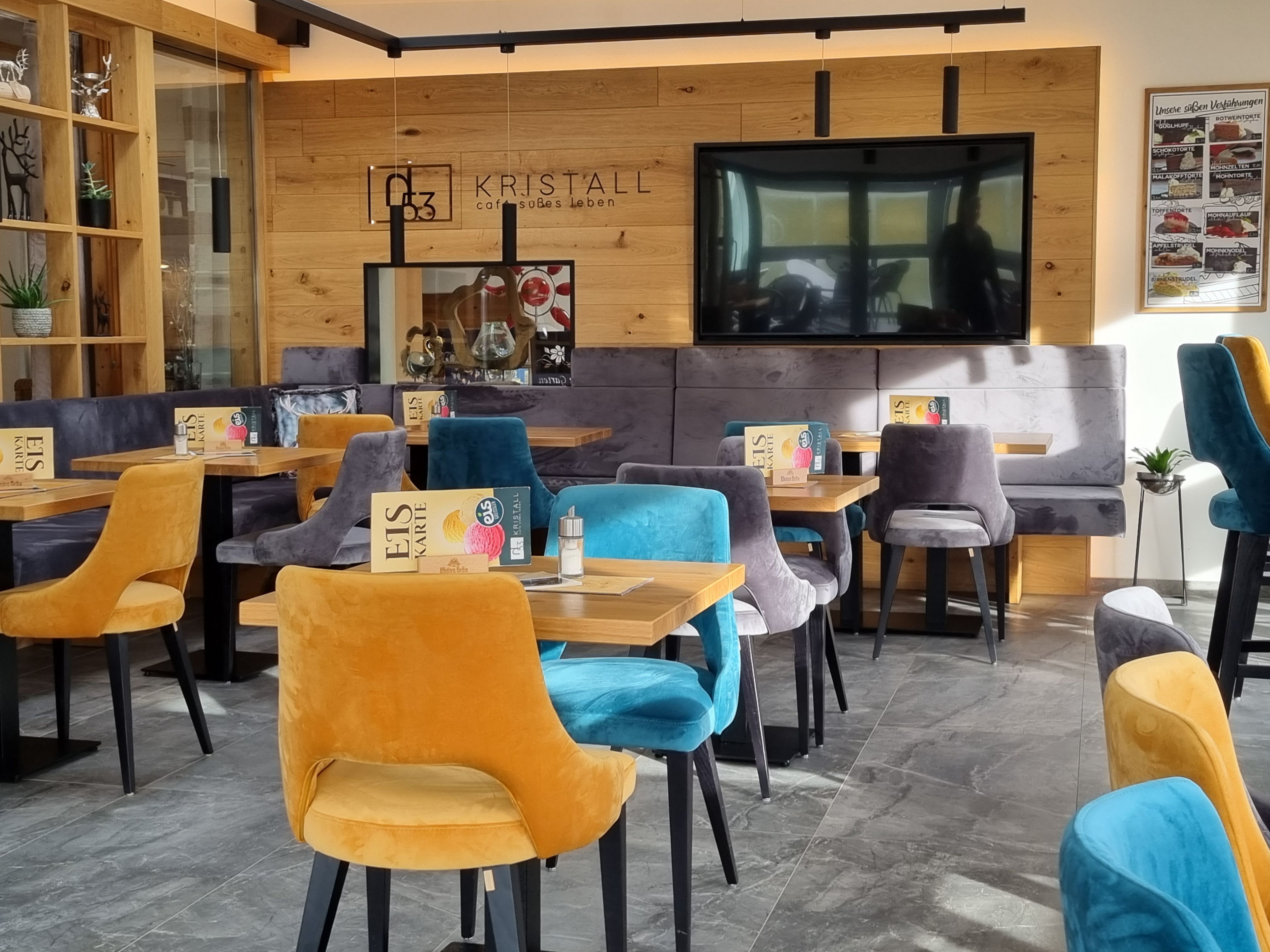 Egy modern kávézó belső nézete színes bársonyszékekkel és fából készült falakkal.