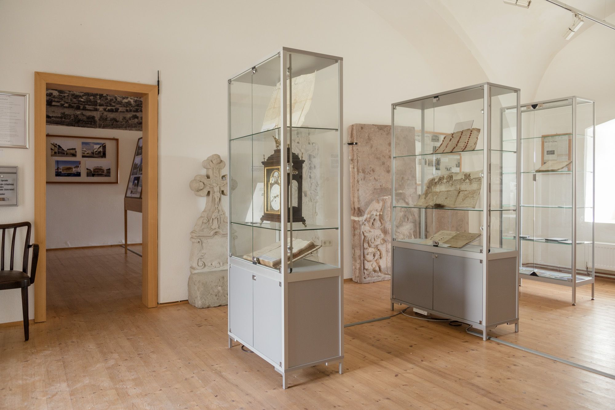 Egy múzeum belső nézete történelmi dokumentumokat és tárgyakat tartalmazó vitrinekkel.