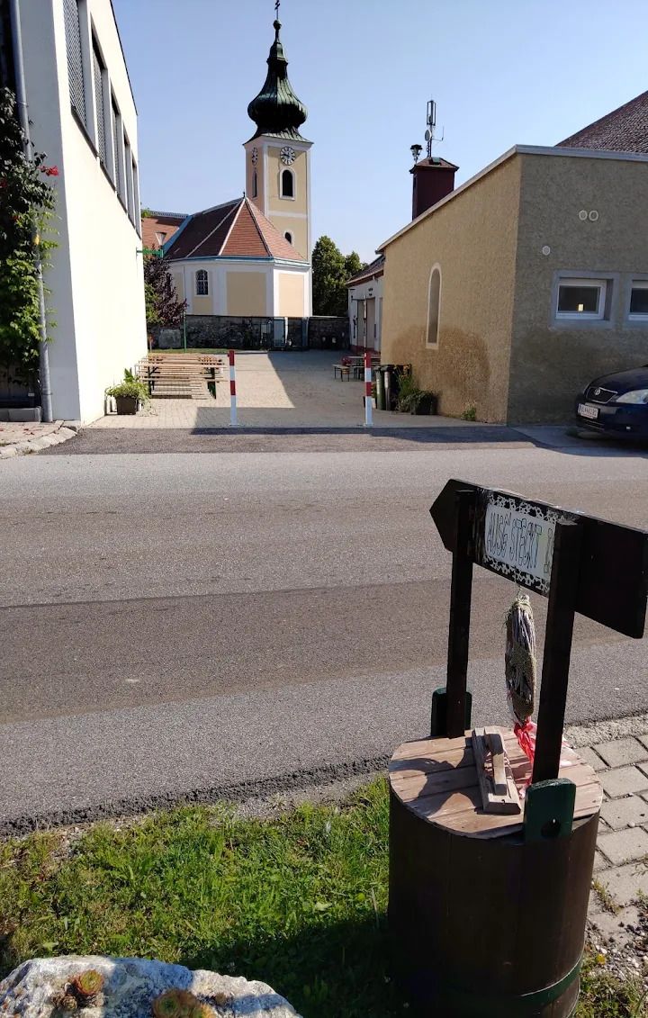 Hagyományos borozó Thaller Wolfsthal, kilátás a belső udvarra borasztalokkal, a háttérben egy templom látható 