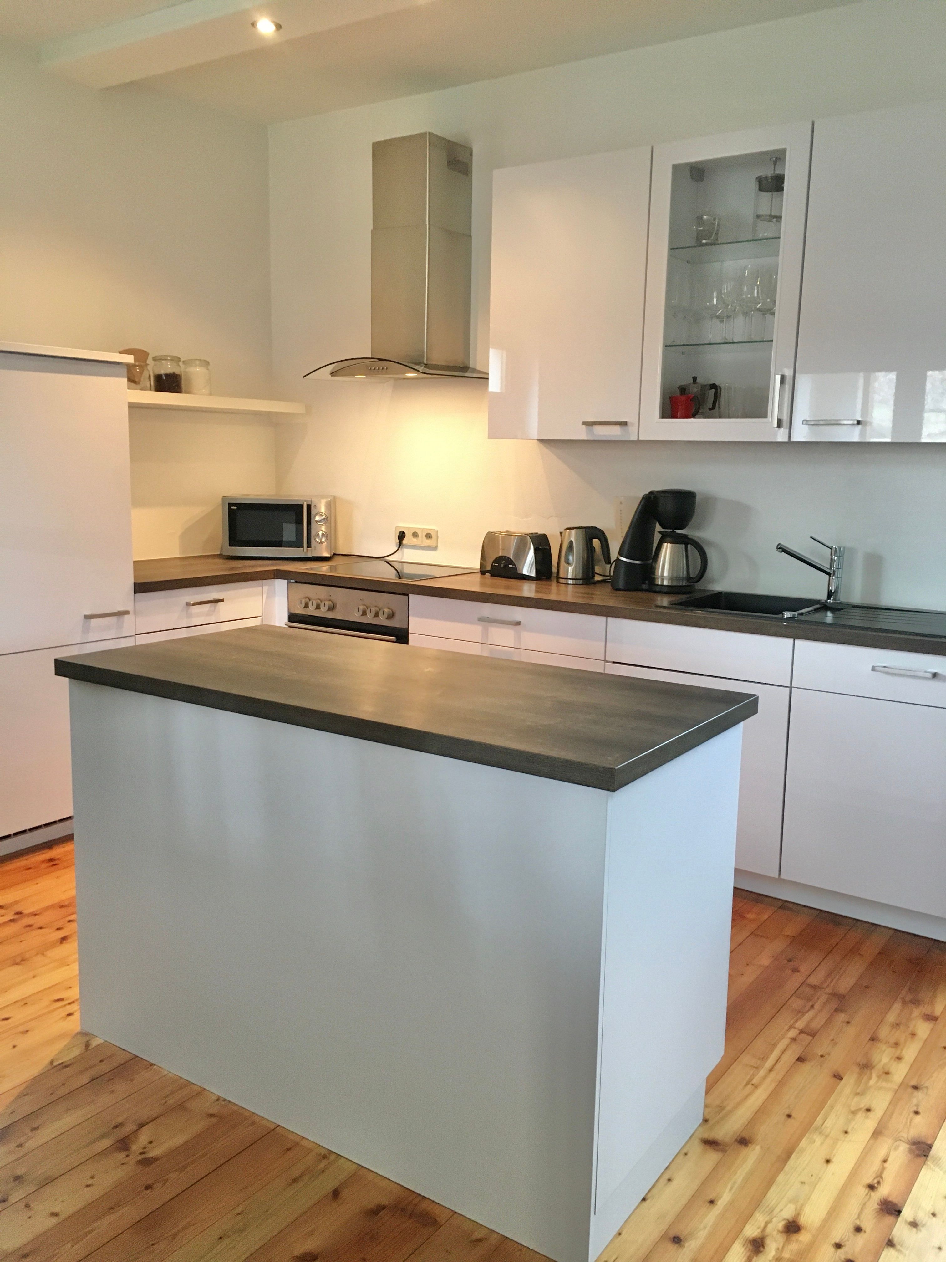 Modern konyha szigettel, fehér szekrényekkel és készülékekkel.