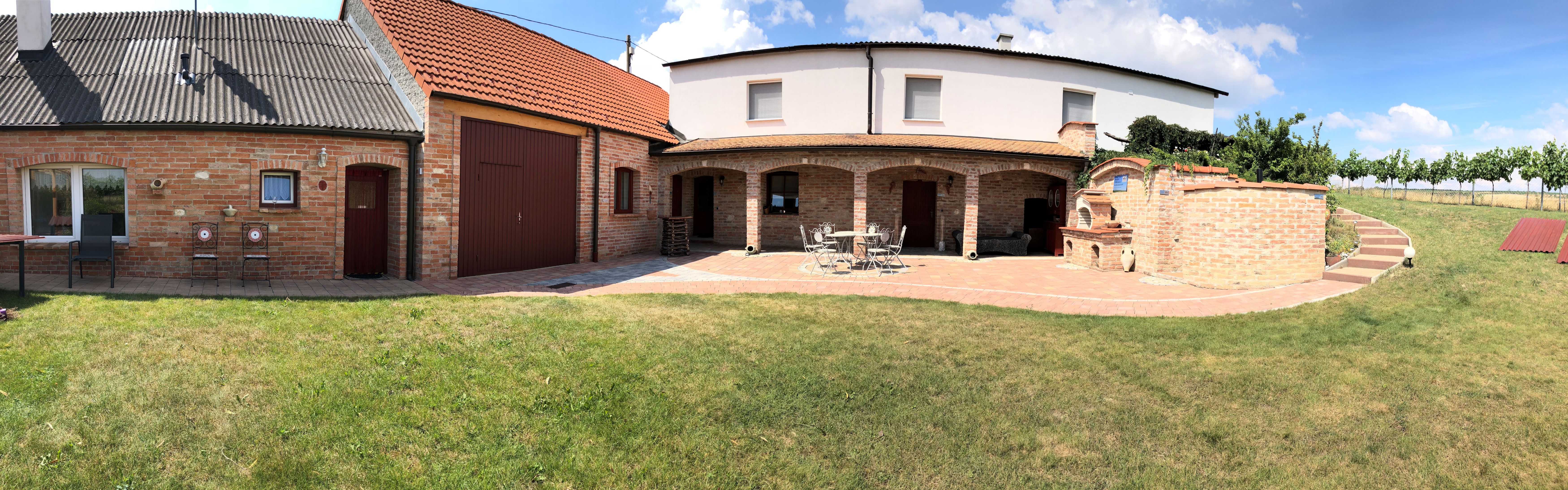 Téglaépület kerttel és terasszal napos időben.