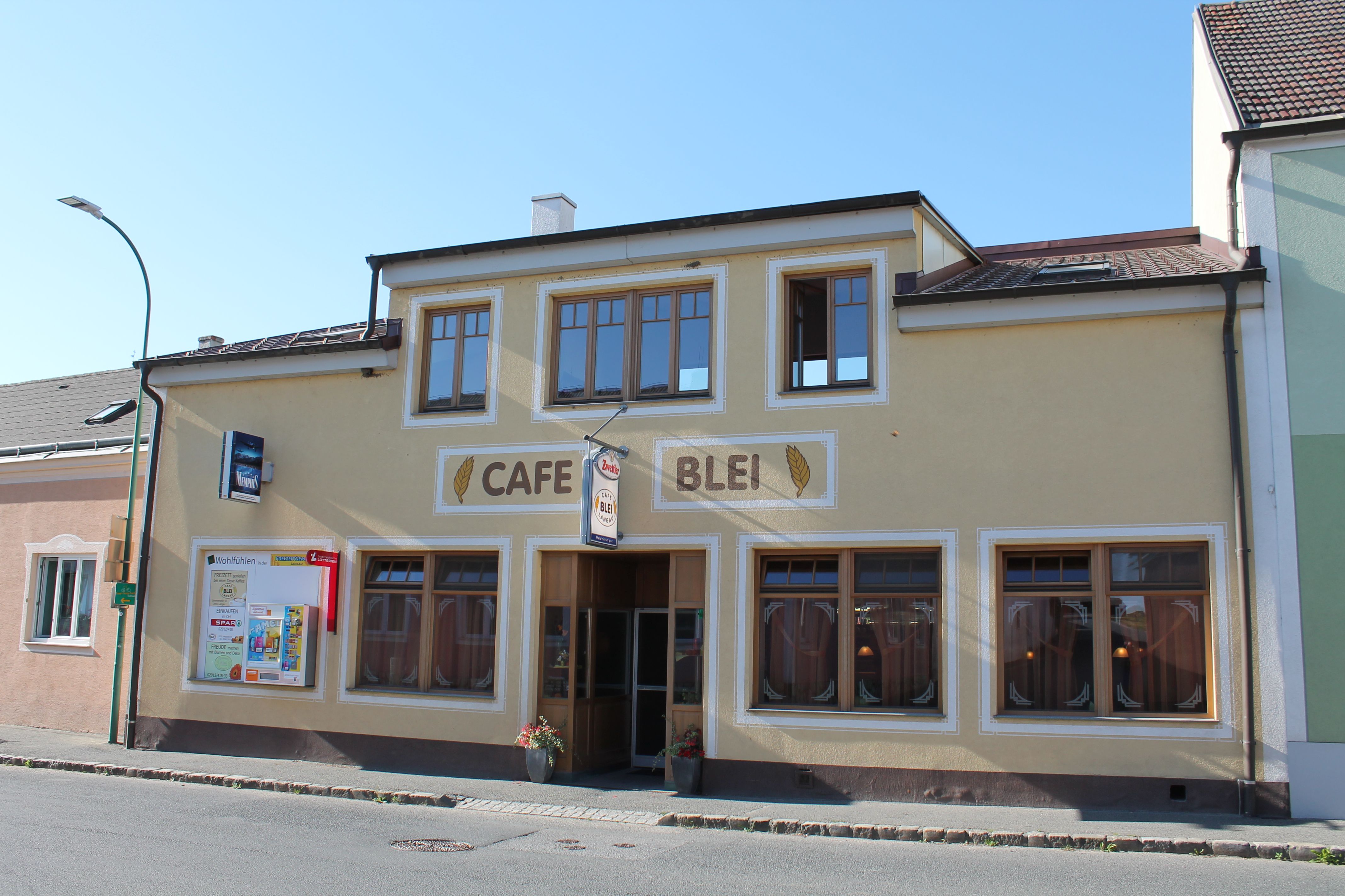 A Café Blei külső nézete sárga homlokzattal és nagy ablakokkal.