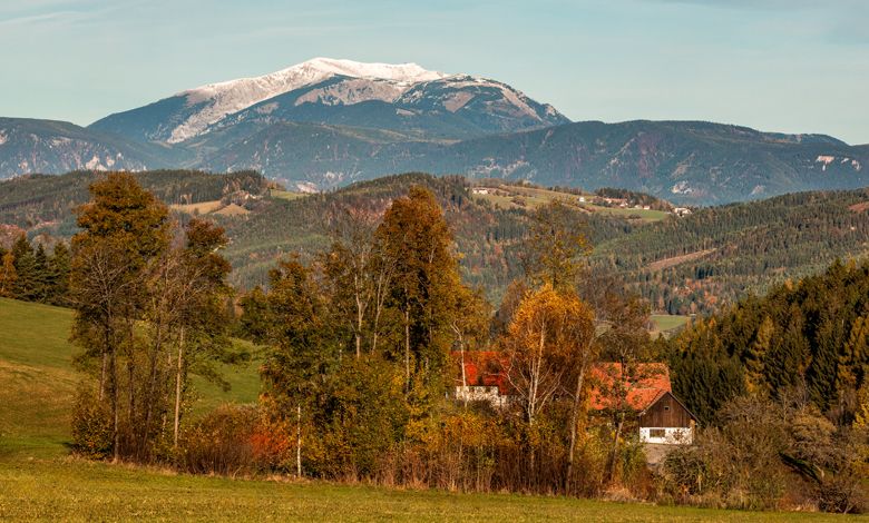 Tájkép hegyekkel, fákkal és egy házzal ősszel.