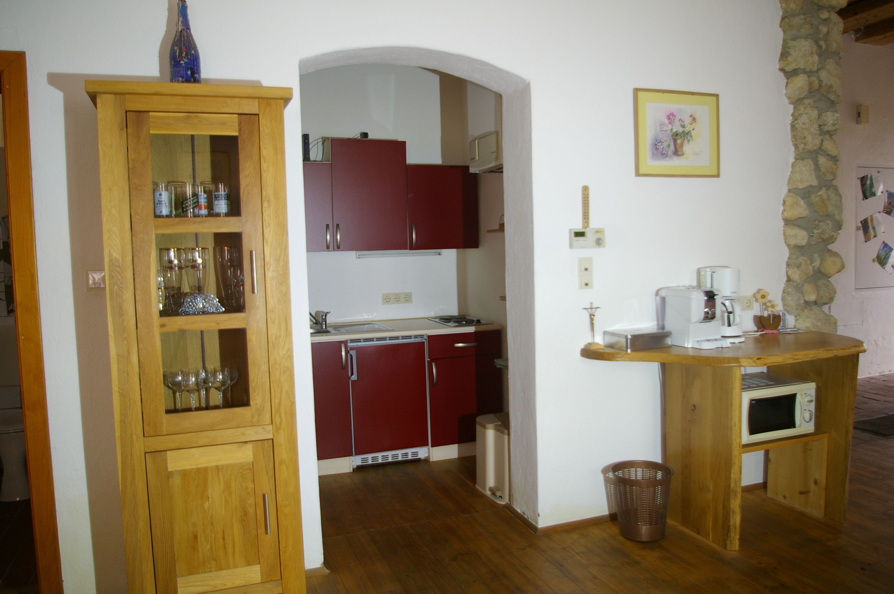 Kis konyha fabútorokkal, piros szekrényekkel és kávéfőzővel.