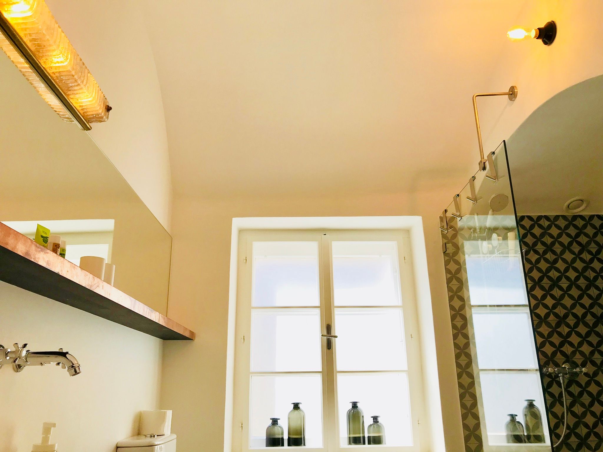 Modern fürdőszoba üvegzuhannyal és dekoratív csempével.