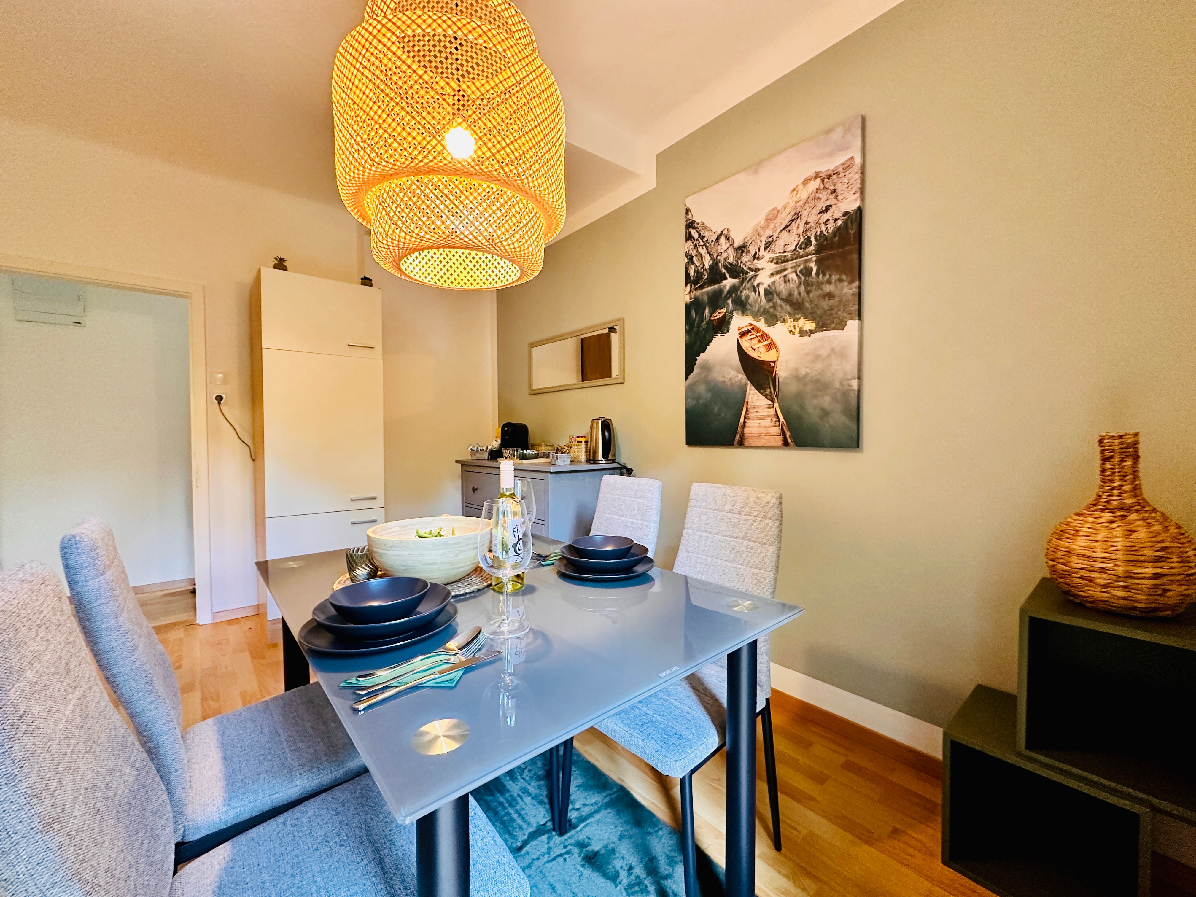 Étkező üvegasztallal, szürke székekkel és nagy lámpaernyővel.