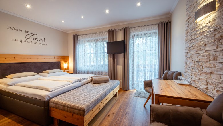 Hangulatos hálószoba franciaággyal, fabútorokkal és kőfallal.