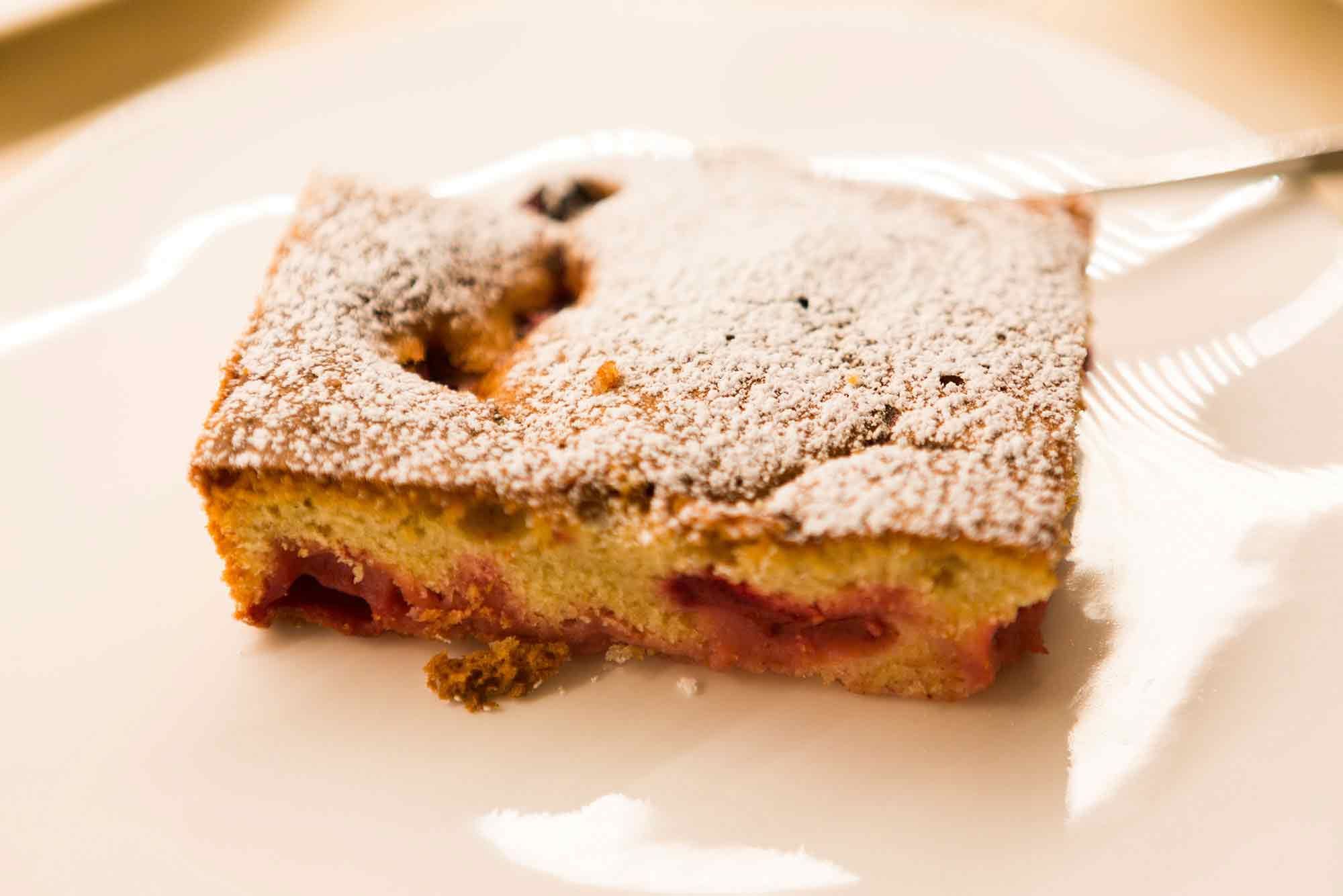Egy szelet házi készítésű torta porcukorral meghintve egy tányéron.