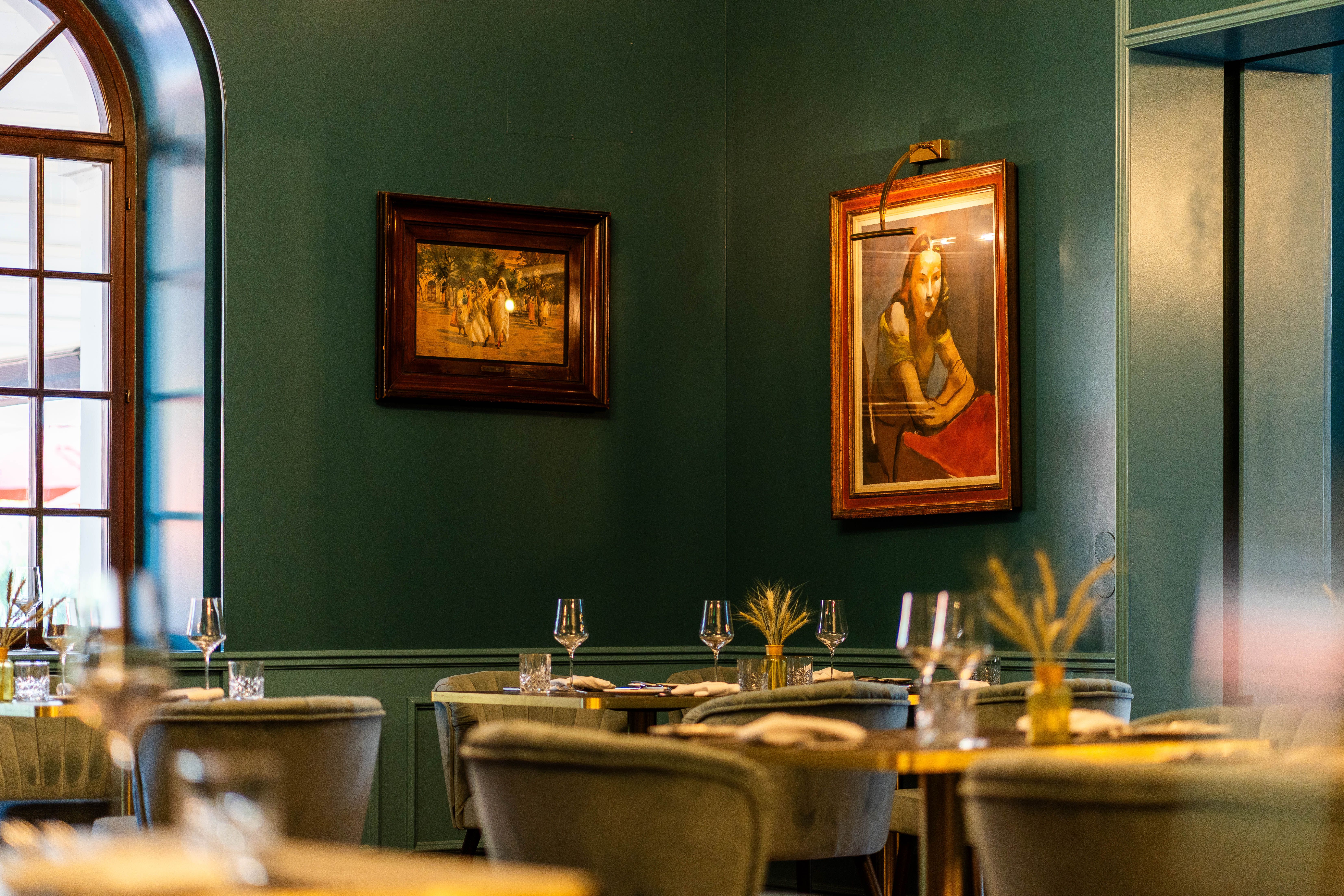 A Grafenegg Hotel & Restaurant belső tere terített asztalokkal, zöld falakkal, nagy ablakokkal és keretezett képekkel.