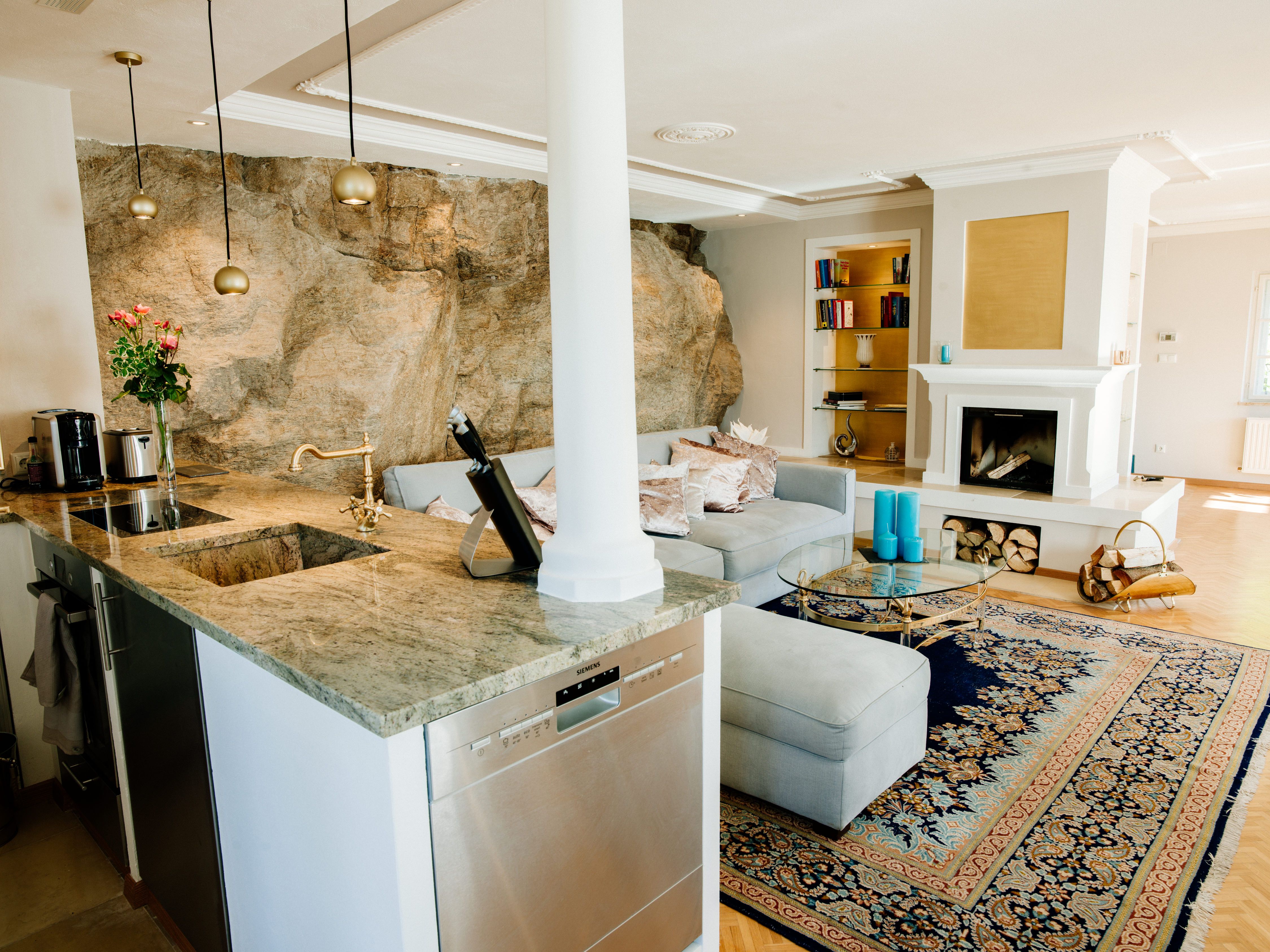 Elegáns nappali kandallóval, szőnyeggel és nyitott konyhával.