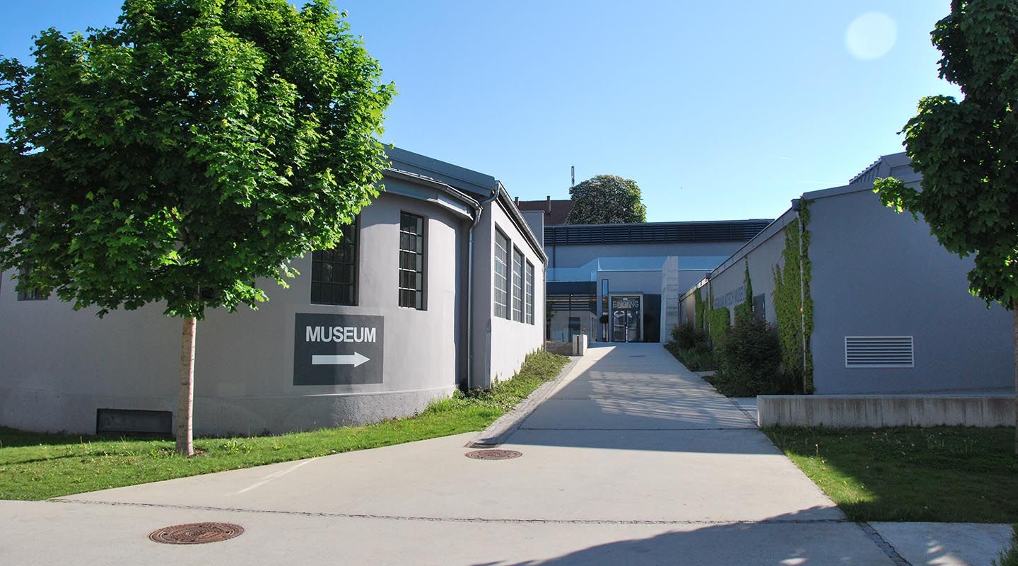 A MAMUZ Múzeum bejárata Mistelbachban táblával és fákkal.