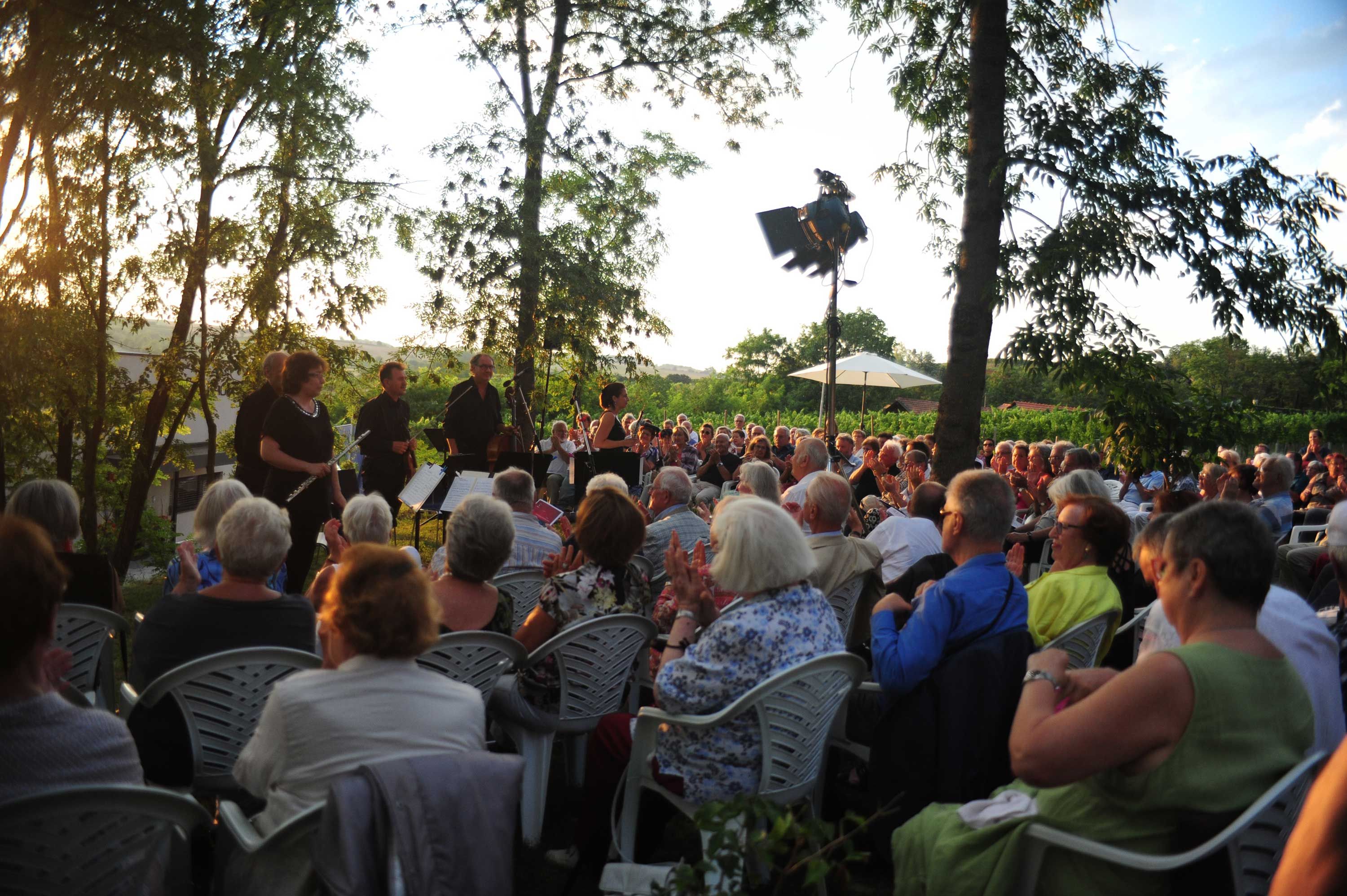 Szabadtéri koncert zenekarral és közönséggel naplementekor.