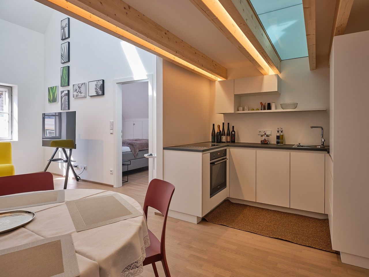 Modern konyha fagerendákkal, étkezőasztallal és kilátással a hálószobába.