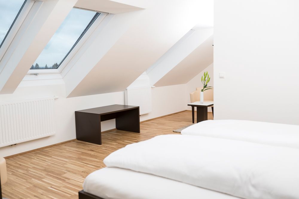 Modern vendégszoba tetőablakokkal, fapadlóval és minimalista bútorokkal.