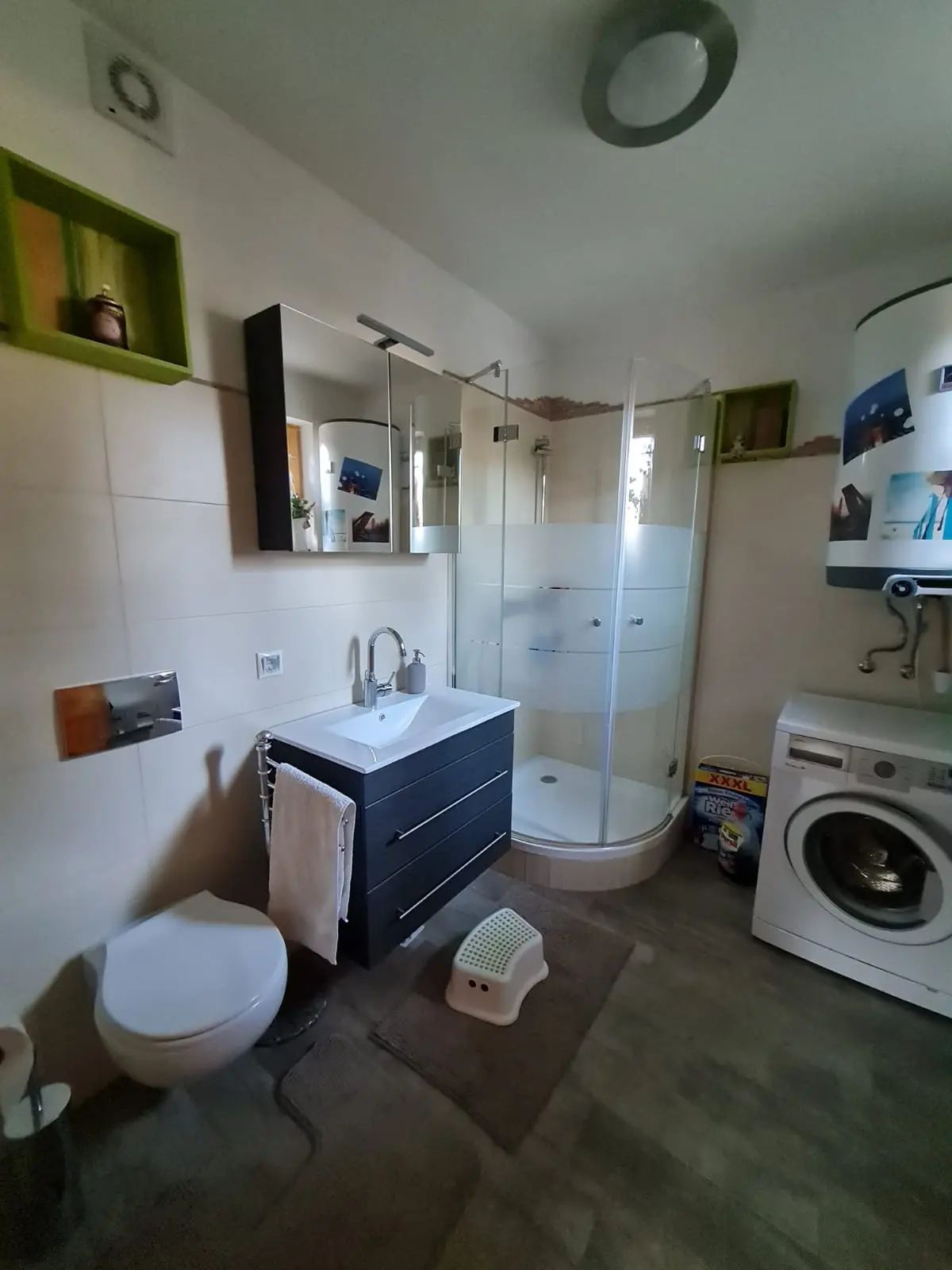 Modern fürdőszoba zuhanyzóval, mosdóval, WC-vel és mosógéppel.