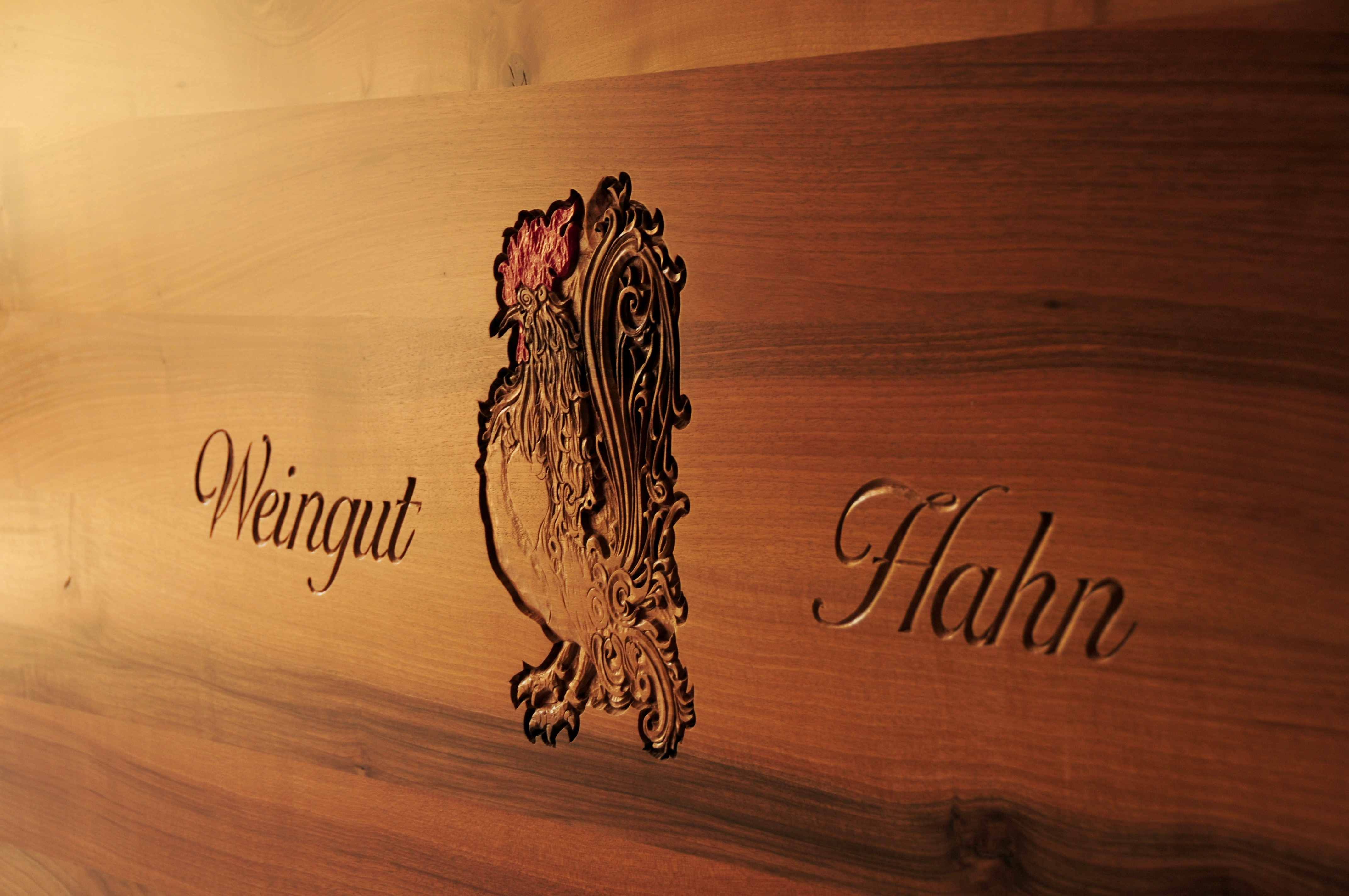 Fából készült tábla gravírozott kakassal és "Weingut Hahn" felirattal.