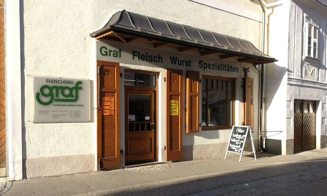 A Graf hentesüzlet külső nézete faajtókkal és reklámtáblával.