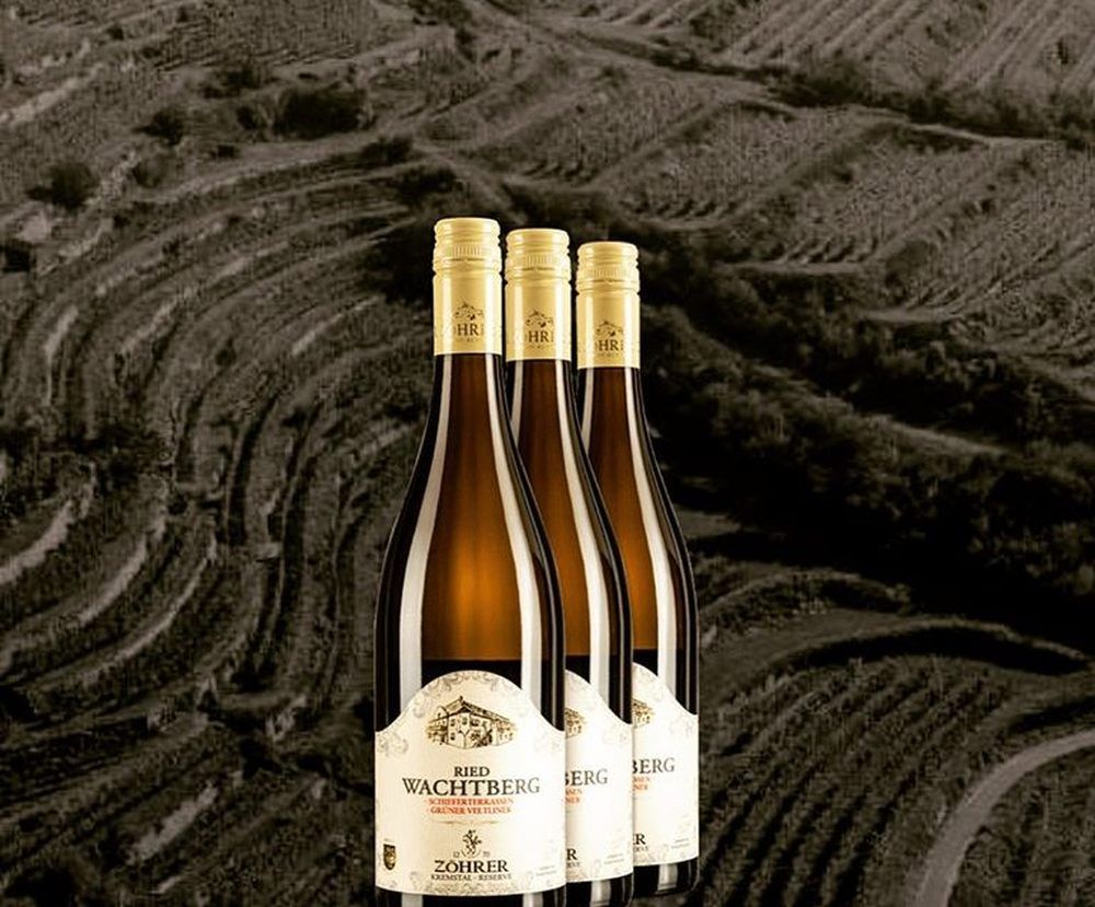 Három üveg bor a szőlőskertek hátterében.