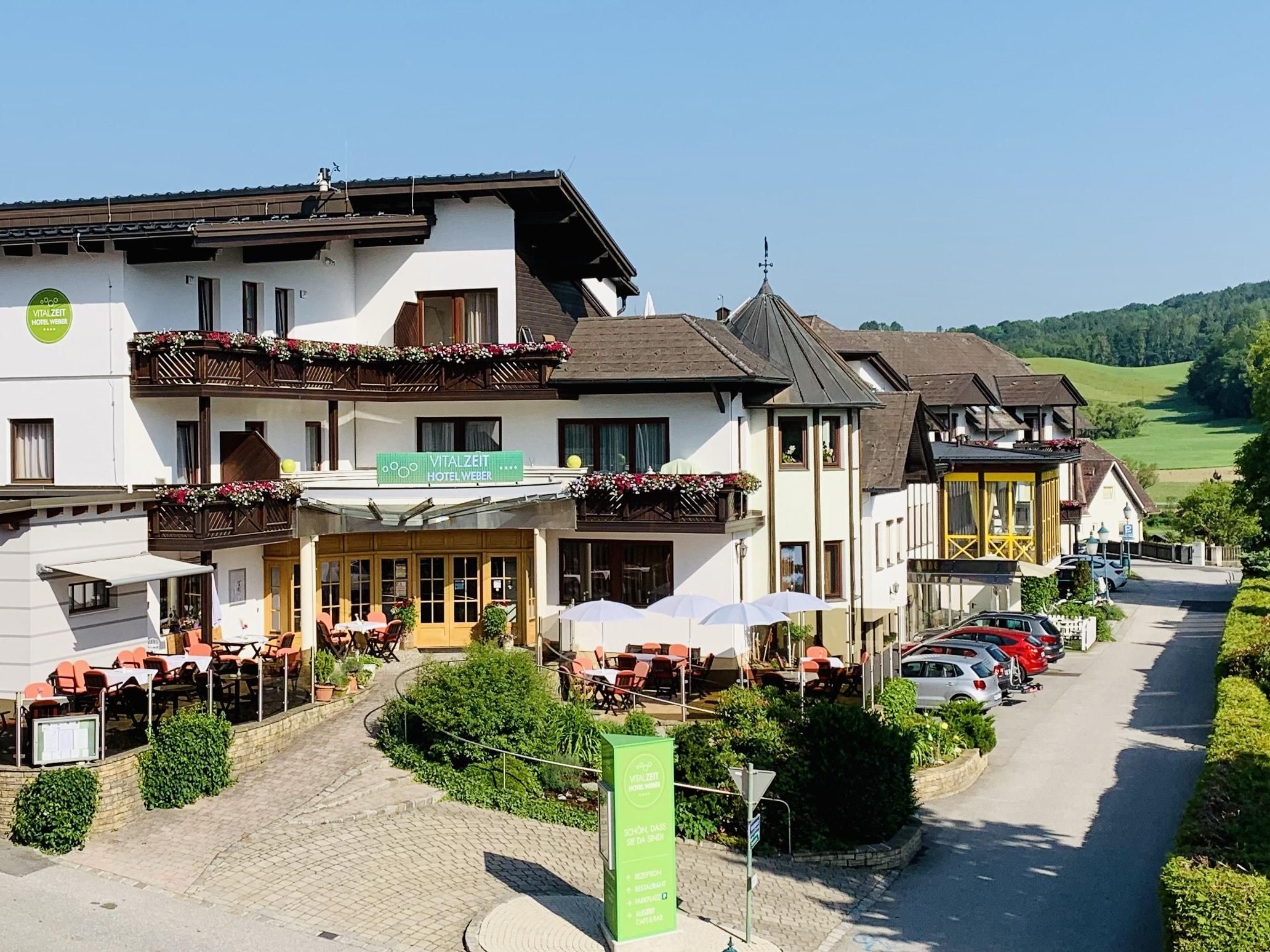 A VitalZeit Hotel Weber külső nézete a terasszal és a környező tájjal.