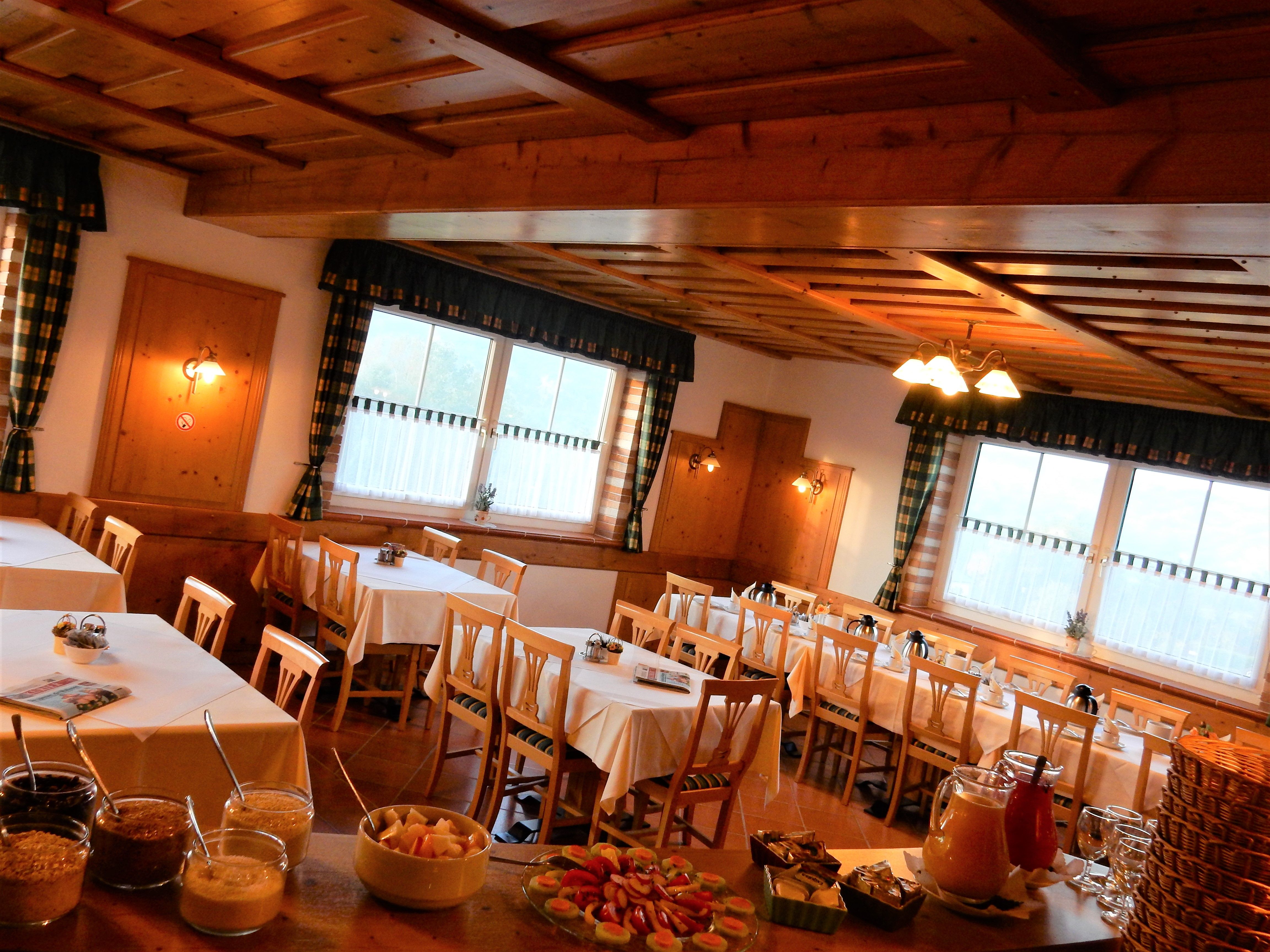 Hangulatos reggelizőterem fabútorokkal és terített asztalokkal.