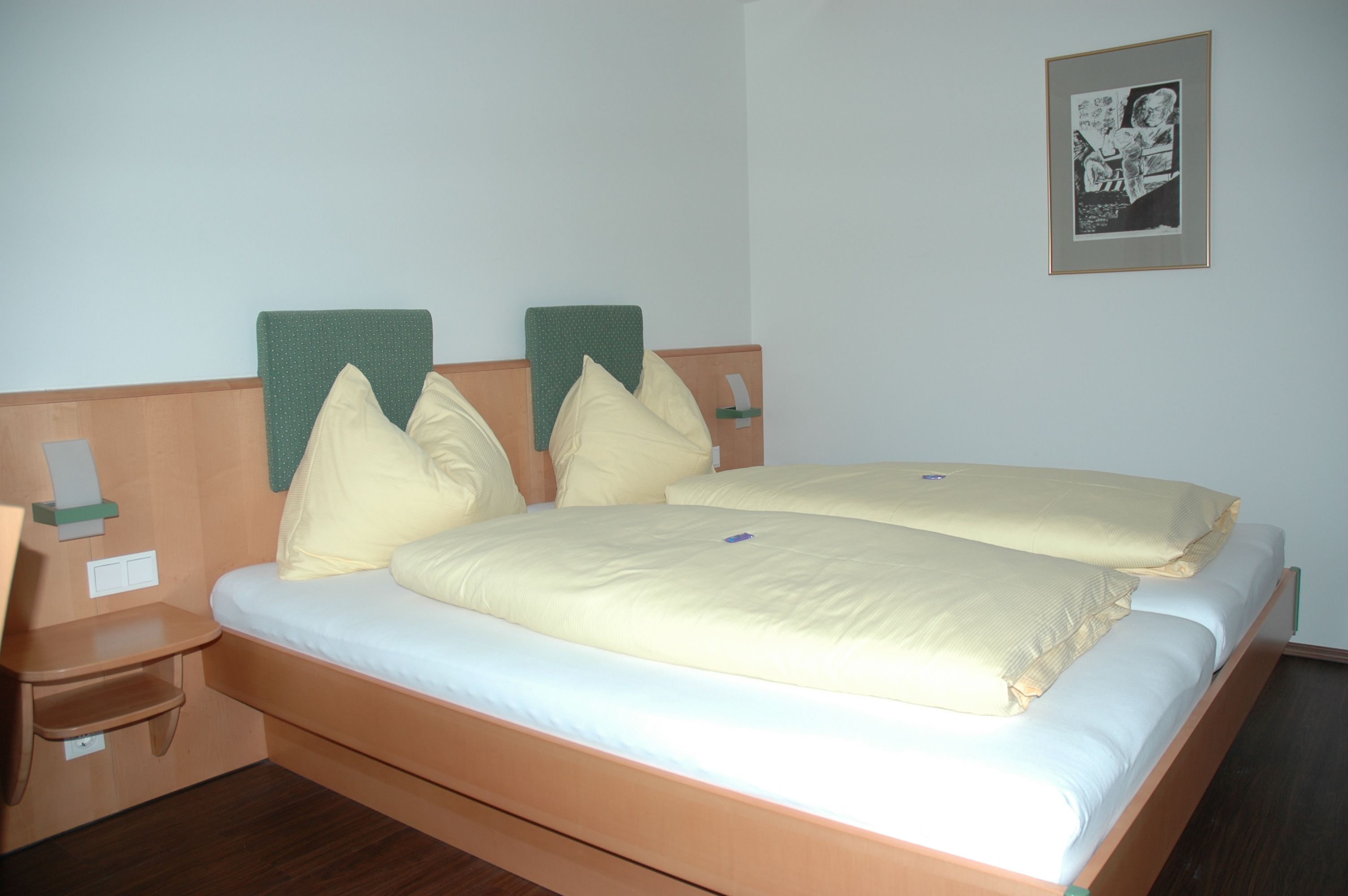 Hotelszoba franciaággyal, sárga ágyneművel és freskóval.