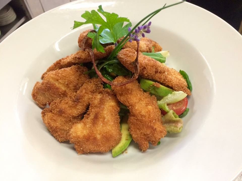 Egy tányér saláta és sült étel, fűszernövényekkel díszítve.