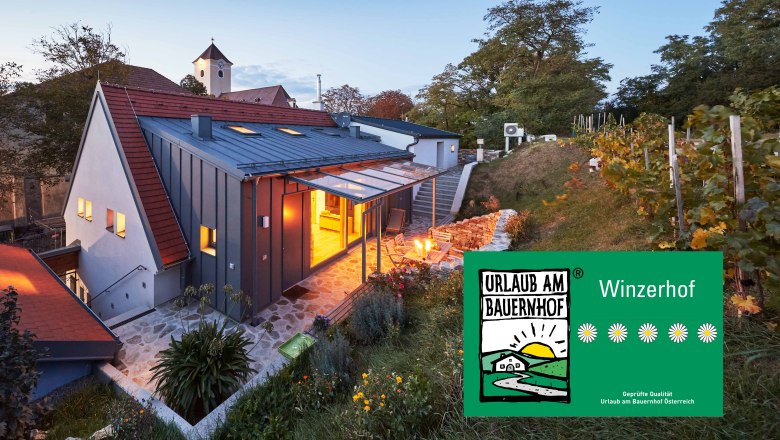 Weinviertler Kellerstöckl, © Andreas Hofer Egy modern pince a Weinviertelben alkonyatkor, szőlővel és kerttel körülvéve. Egy tábla jelzi: "Nyaralás egy tanyán".