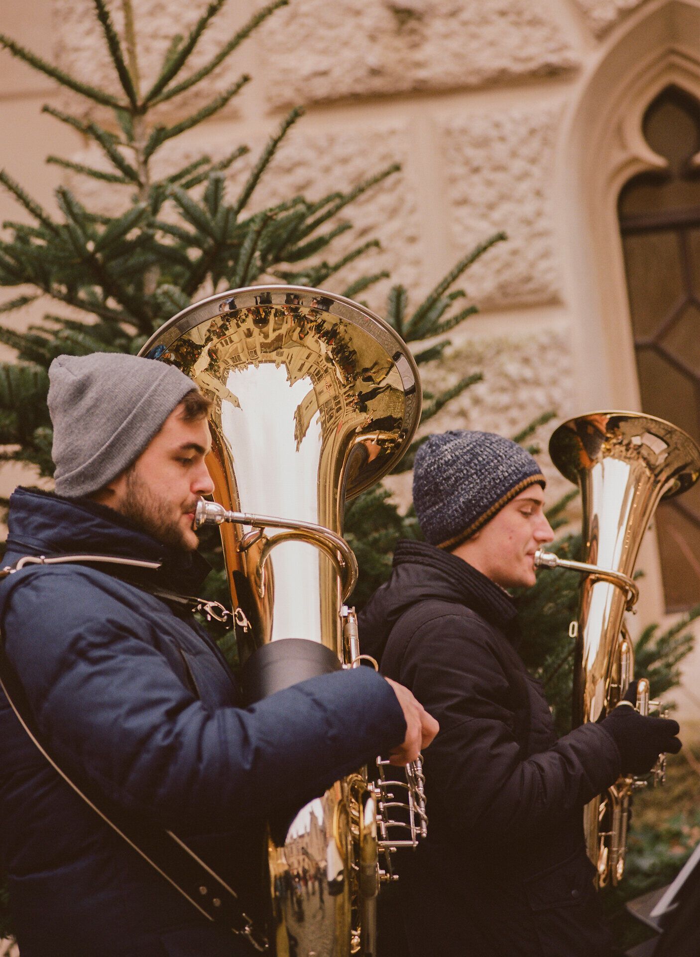 Zwei Blechbläser spielen beim Grafenegger Advent im Freien, warm gekleidet vor historischer Schlossfassade und Tannenbaum.