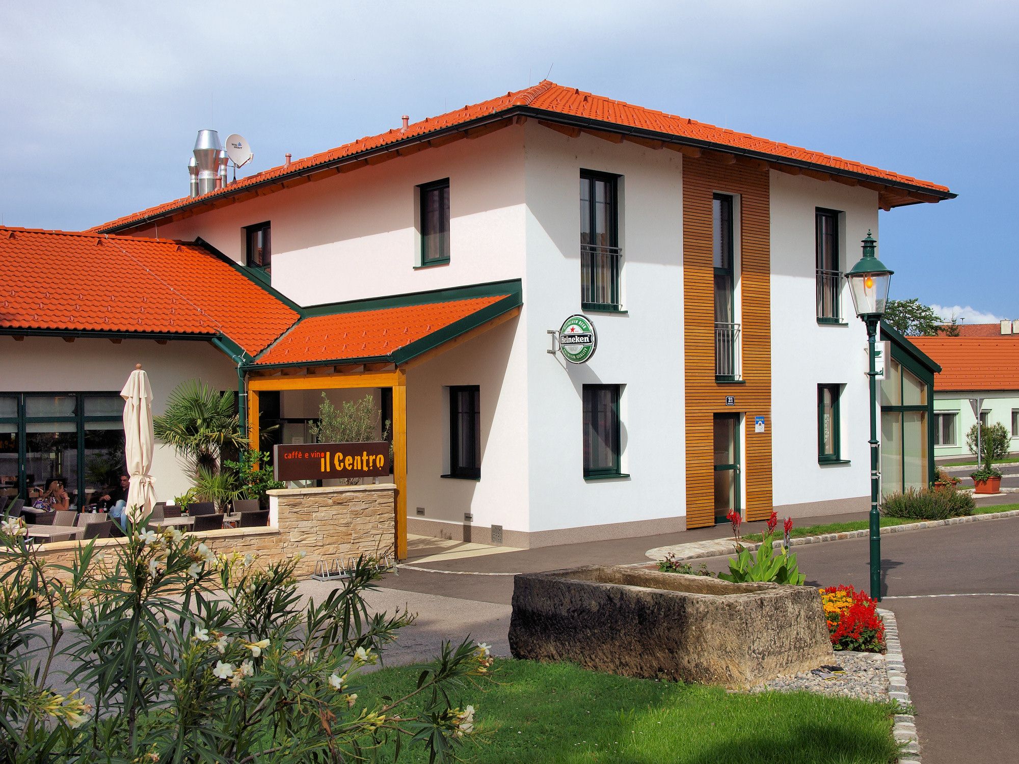 Egy vörös tetős, teraszos épület külső nézete, "caffè e vini Centro" felirattal.