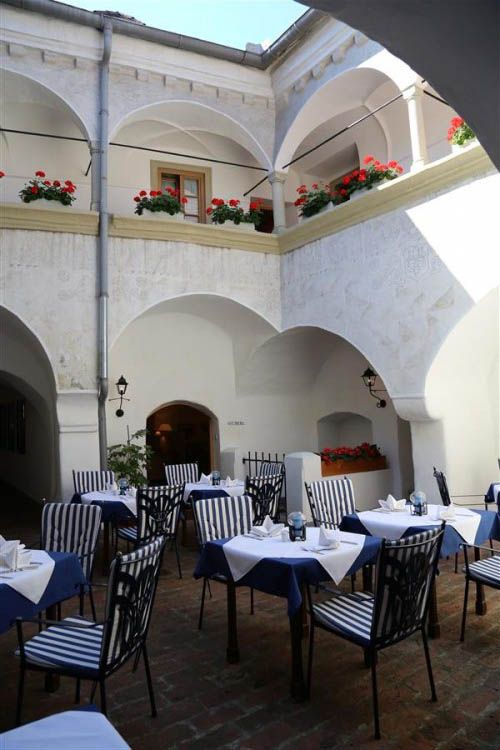 Egy fogadó belső udvara terített asztalokkal és virágokkal.