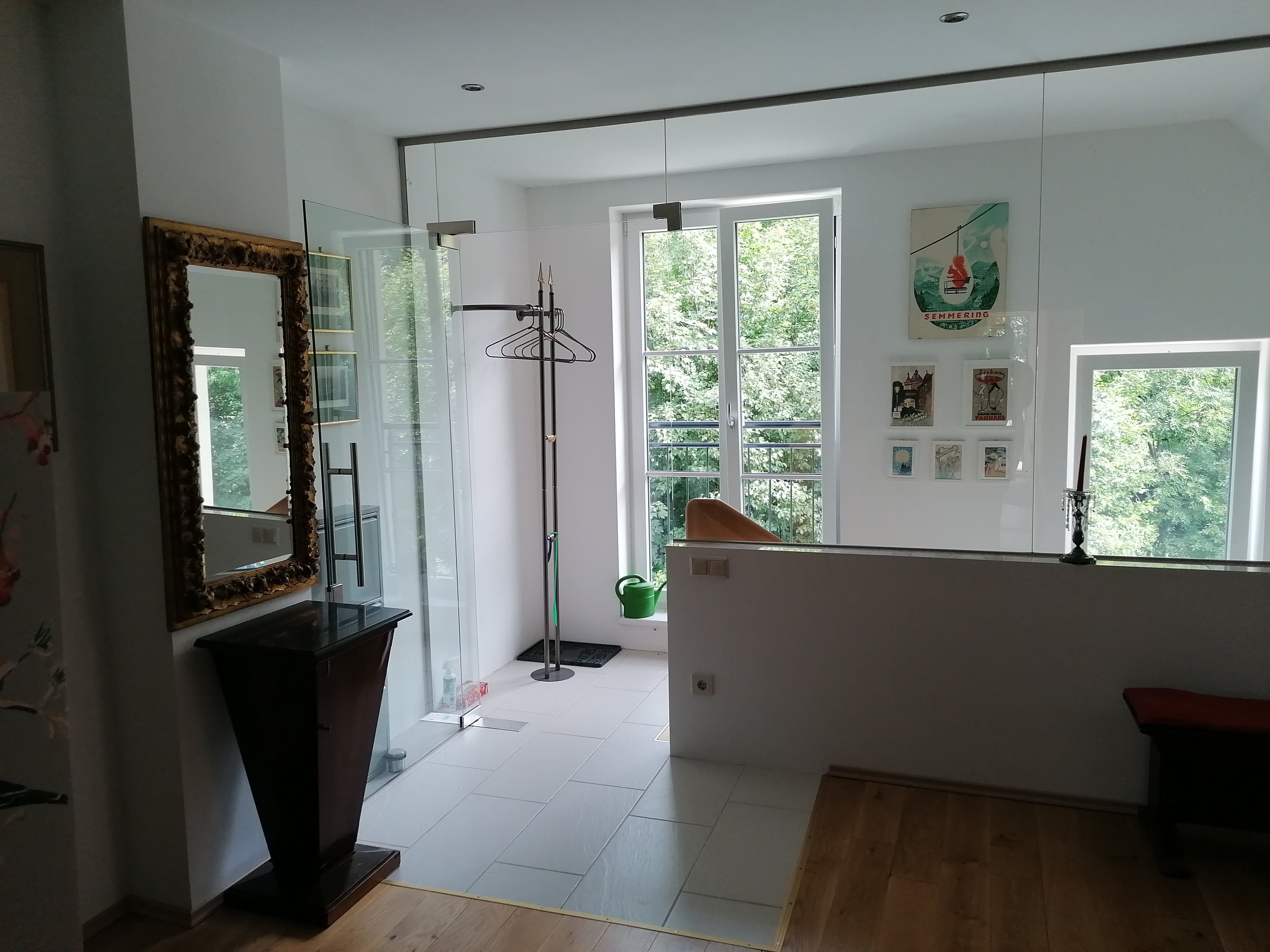 Egy nyaraló apartman előtere tükörrel, ruhatartóval és képekkel a falon.