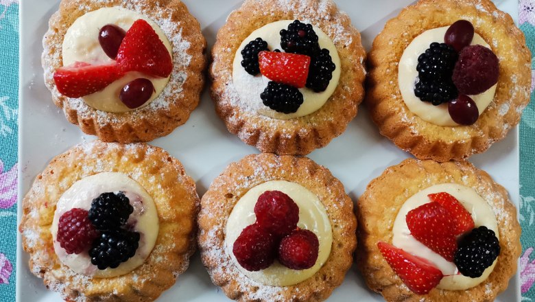 Hat kis gy&uuml;m&ouml;lcstorta feh&eacute;r t&aacute;ny&eacute;ron, bogy&oacute;kkal &eacute;s tejsz&iacute;nnel d&iacute;sz&iacute;tve.