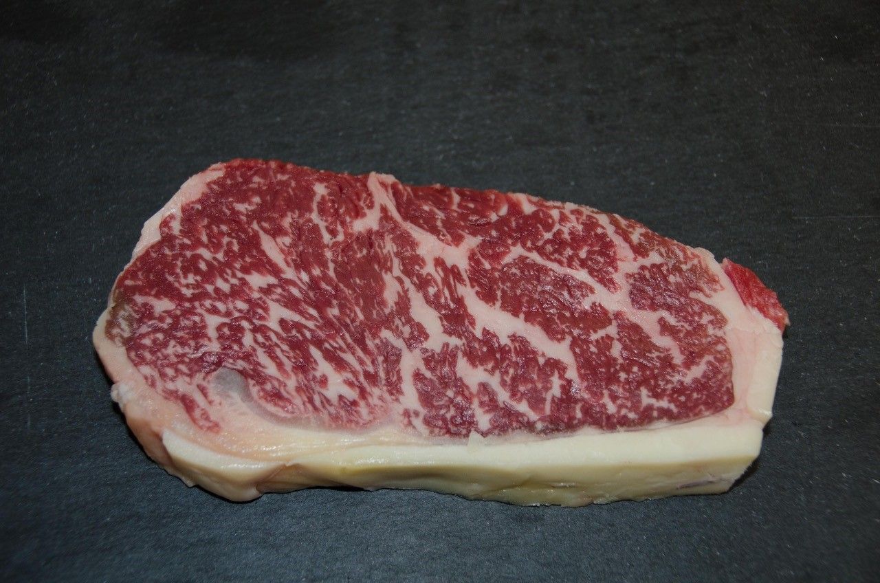 Egy darab Wagyu marhahús erős márványozottsággal, fekete alapon.