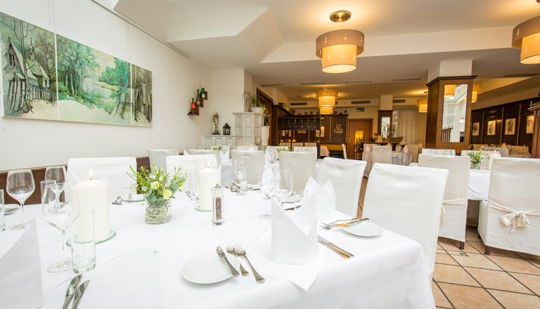 Der Wintergarten mit einem gedeckten Tisch und wei&szlig;en St&uuml;hlen.