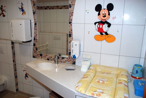 Gyermekbarát fürdőszoba Mickey egér dekorációval és pelenkázóasztallal.