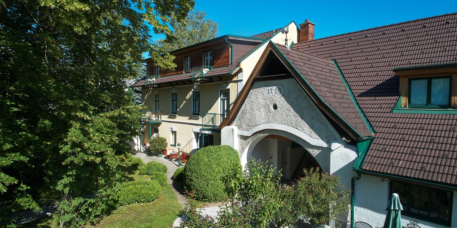 Landhaus Puchbergerhof a kerttel és a fákkal az előtérben.