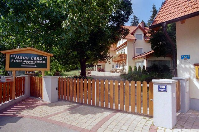 A Haus Lenz bejárata fakerítéssel és táblával, fákkal körülvéve.