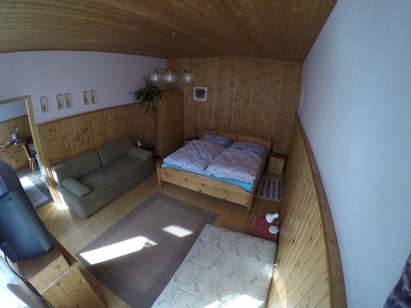 Hangulatos hálószoba fából készült falakkal, franciaággyal, kanapéval és szőnyeggel a fapadlón.