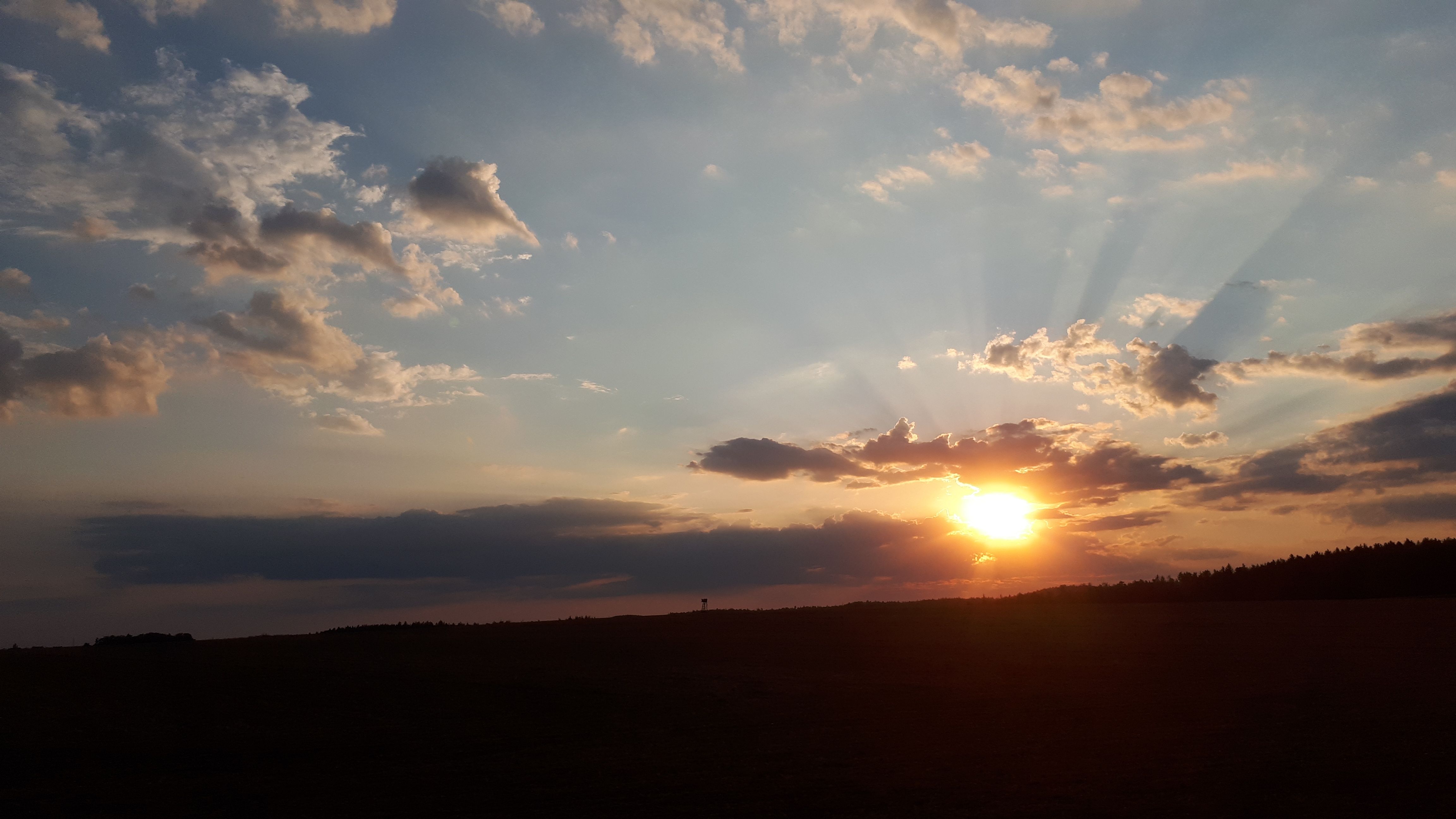Naplemente felhőkkel és sugarakkal az égen.