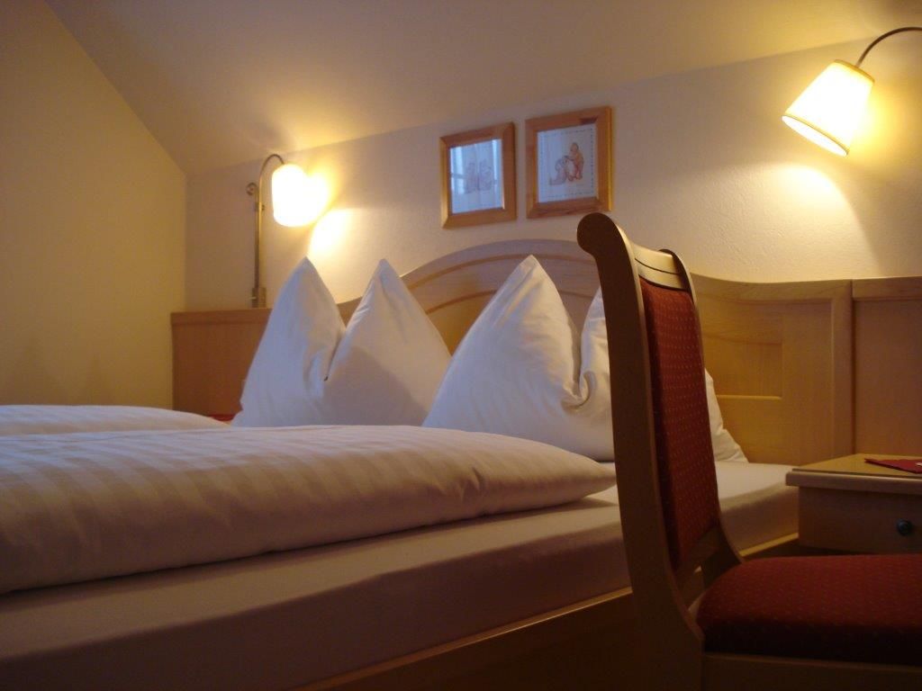 Hangulatos vendégszoba franciaággyal, két éjjeli lámpával és egy székkel.